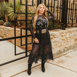 Woman wearing a black western style dress with embroidery on top