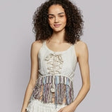 Woman wearing a beige sleeveless crop top with lace-up front and colorful fringes.