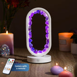 Decorative lamp with purple gemstones on a wooden surface with candles and a remote control.